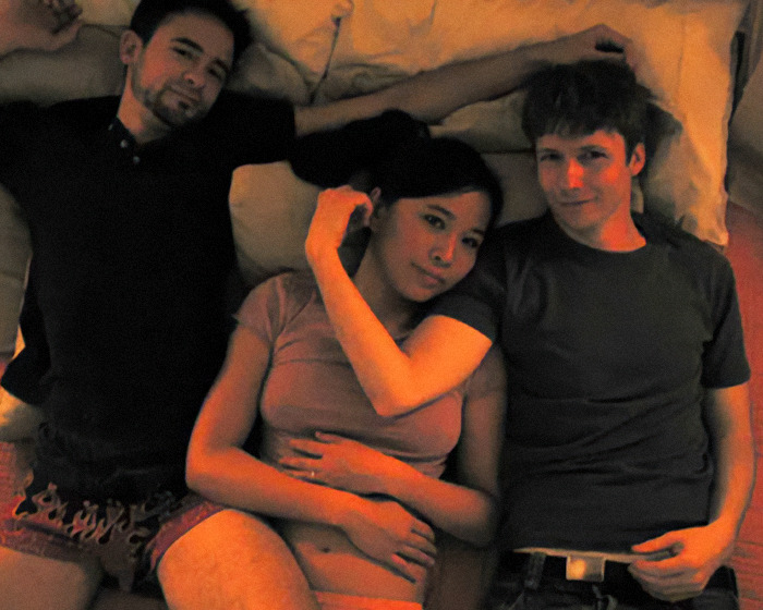 Tres actores acostados juntos en una escena íntima, relacionados con estrellas de cine que hicieron el amor real.