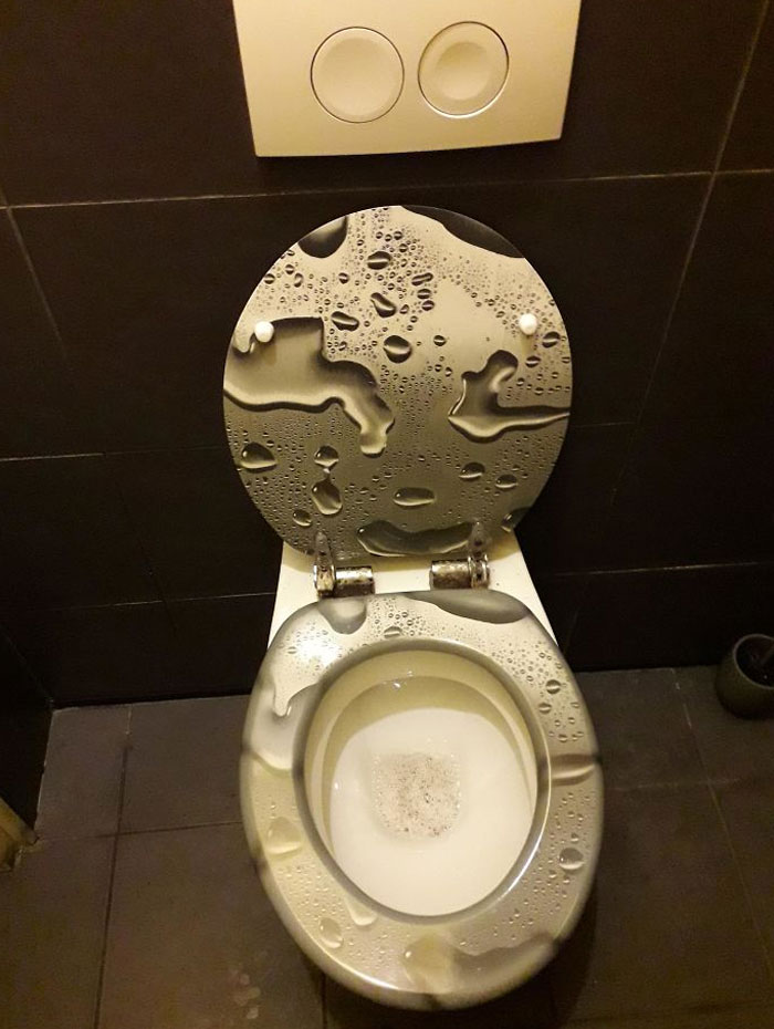 Asiento de inodoro con diseño de gotas de agua que crean un fallo de diseño divertido y confuso en el baño.