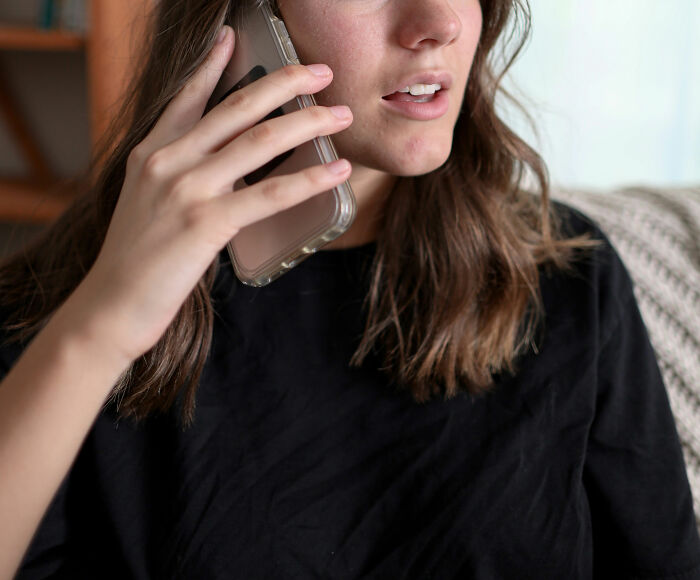 Mujer hablando por teléfono con expresión seria, mostrando que usar Reddit no es para personas sensibles.