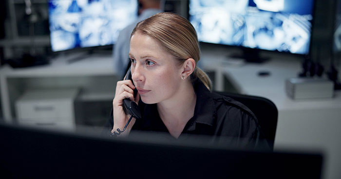 Mujer trabajando en seguridad, usa teléfono en centro de monitoreo con pantallas, revela cosas inquietantes de profesiones.