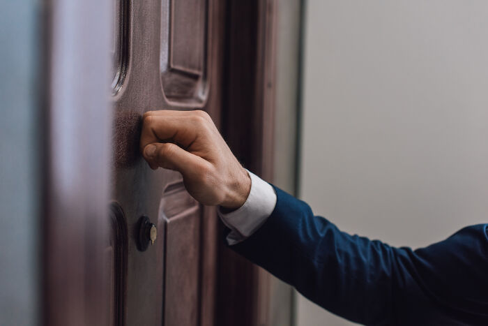 Mano golpeando la puerta de madera representando momentos en Reddit que no son para débiles de corazón.
