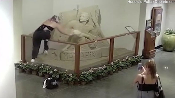 Persona prepotente trepando una escultura en museo mientras es grabada, mostrando comportamiento con derecho exagerado en internet.