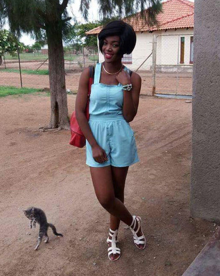 Mujer posando para foto mientras un gato roba la atención en un momento divertido de mascotas arruinando la toma perfecta.
