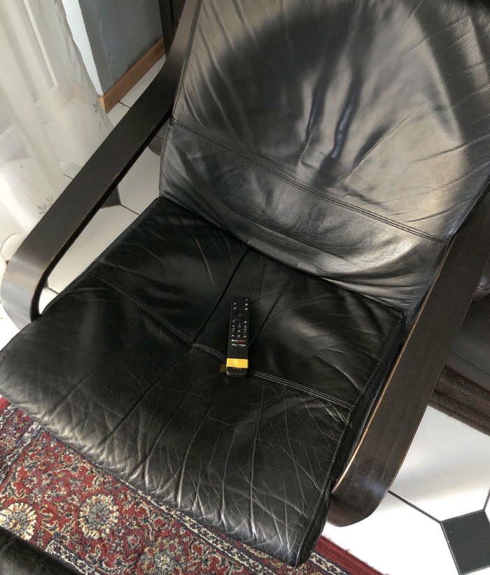 Control remoto colocado con cinta amarilla en silla negra de cuero, ejemplo de life hacks geniales y prácticos usados por personas.