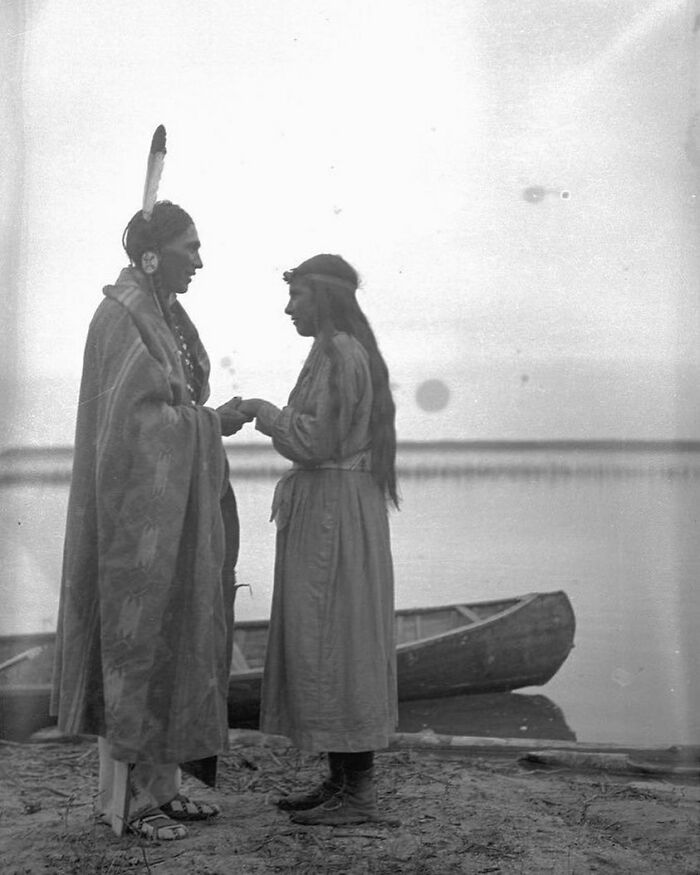 Hombre y mujer nativos americanos frente a un canoa en la orilla, escena histórica poco conocida y significativa. Hombre y mujer nativos americanos frente a un canoa en la orilla, escena histórica poco conocida y significativa.