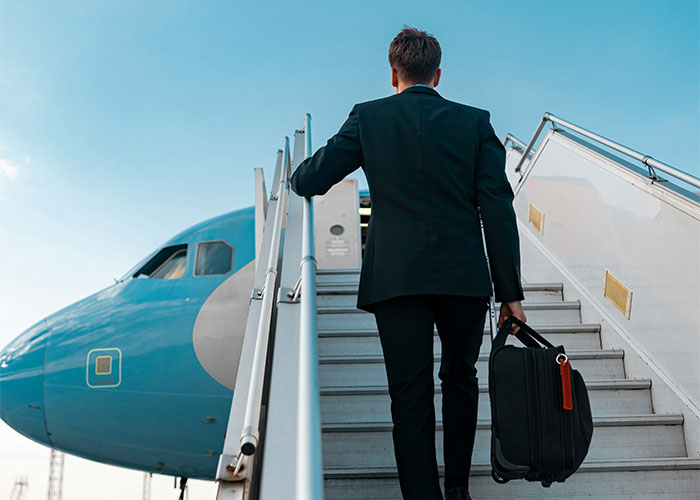 Hombre de negocios subiendo escaleras hacia avión, representando vacíos legales explotados en situaciones límite.