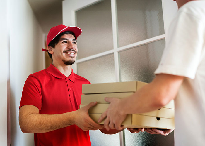 Repartidor sonriente entregando cajas, concepto relacionado a vacíos legales explotados antes de ser descubiertos.