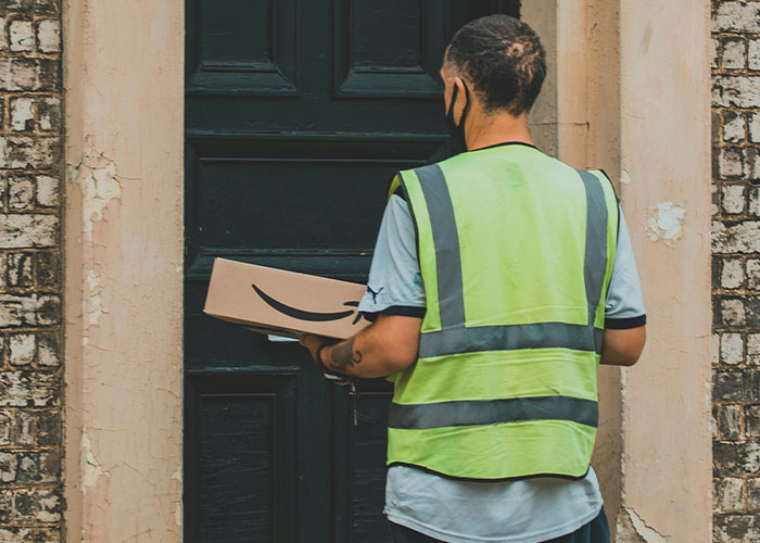 Hombre con chaleco reflejante entregando paquete en puerta, simbolizando vacíos legales explotados antes de ser descubiertos.