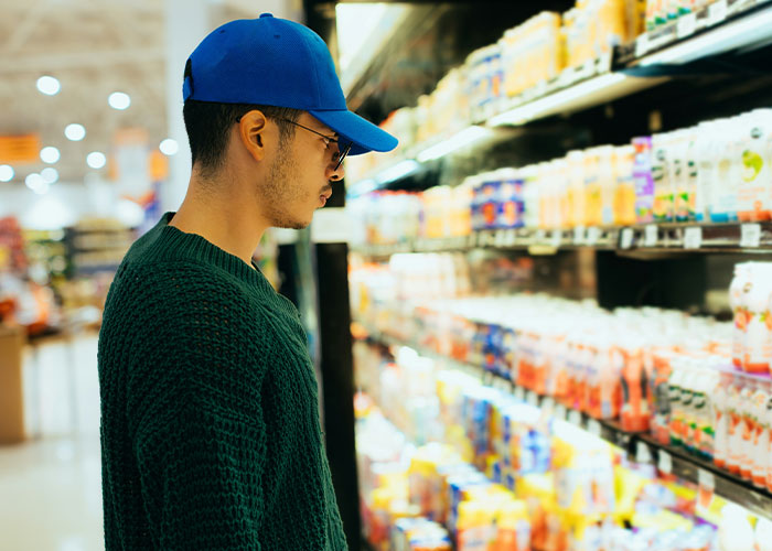 Joven con gorra azul revisa productos en supermercado, ilustrando vacíos legales que fueron explotados.