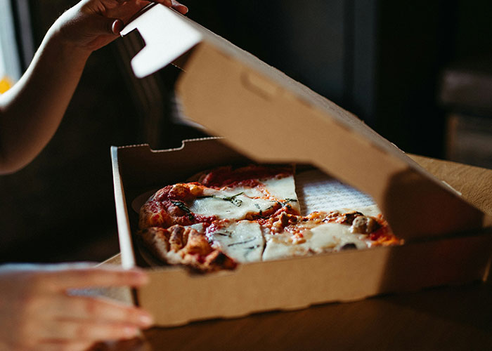Manos abriendo caja de pizza con varias porciones, ilustrando concepto de vacíos legales explotados antes de ser descubiertos.