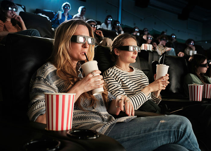 Personas usando gafas 3D y bebiendo refrescos en cine, ilustrando concepto de vacíos legales aprovechados antes de ser descubiertos.