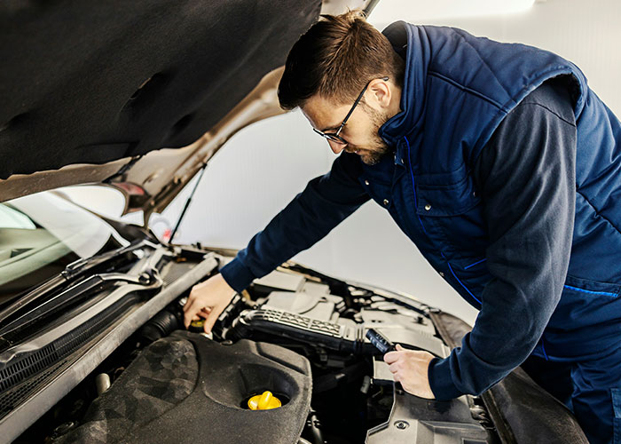 Hombre inspeccionando motor de coche, ilustrando vacíos legales y su explotación antes de ser descubiertos.