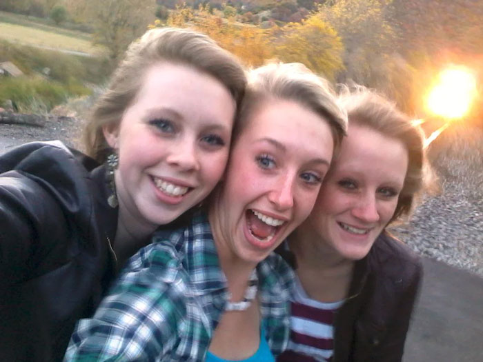 Tres chicas adolescentes posando para una selfie sonriente en un entorno natural momentos antes de una tragedia.