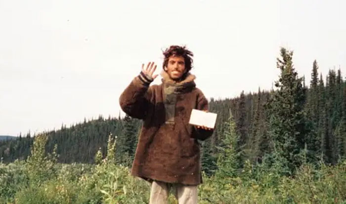 Hombre en bosque sosteniendo objeto, foto tomada segundos antes de un desastre natural inesperado impactante.
