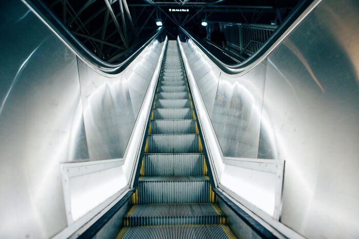 Escalera eléctrica moderna en espacio público con iluminación brillante, simbolizando lo intenso de Reddit para los valientes.