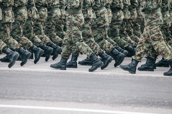 Soldados marchando en formación con uniformes y botas militares en ejercicio militar representando datos inquietantes.