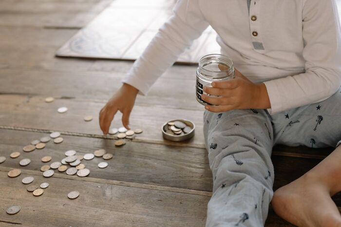 Niño adolescente contando monedas en el suelo, escena que refleja padres cotillas descubriendo secretos inesperados.