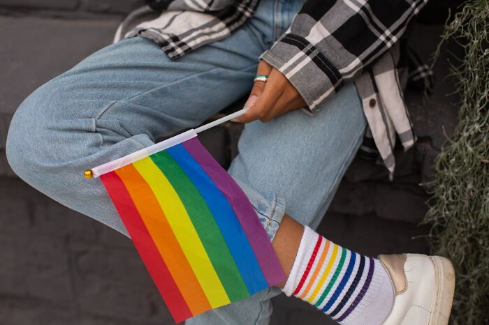 Persona joven con calcetines de colores y bandera arcoíris, simbolizando diversidad y temas adolescentes inesperados.