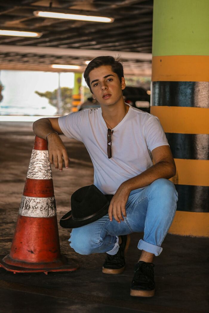 Joven adolescente con camiseta blanca y jeans en estacionamiento, simbolizando padres cotillas y secretos adolescentes.
