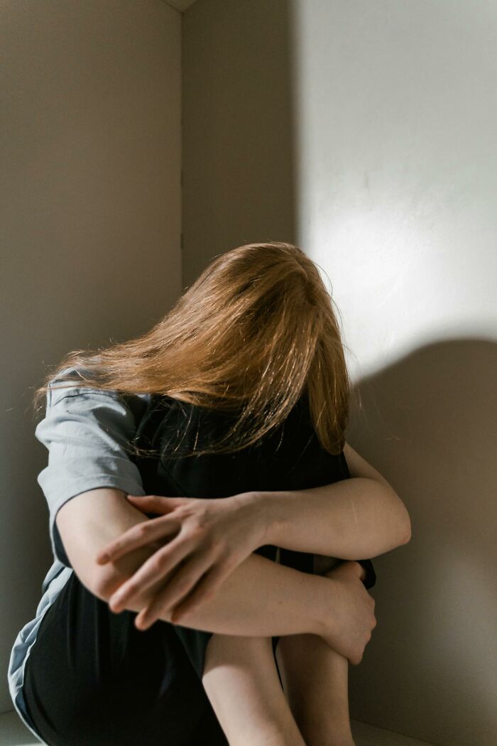 Adolescente abrazándose a sí misma en la esquina, reflejando emociones que padres cotillas pueden descubrir inesperadamente.