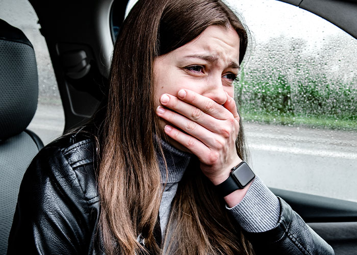 Mujer dentro de un coche con expresión de miedo y cubriéndose la boca tras un encuentro con el mal puro.