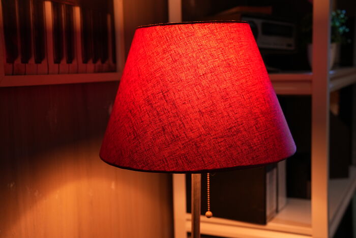 Lámpara de mesa con pantalla roja iluminada en un espacio interior, simbolizando lo intenso de Reddit para quienes no son sensibles.