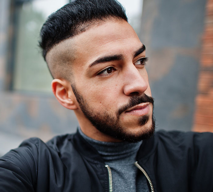 Hombre joven con barba y corte de pelo moderno que refleja experiencias con un psicópata en su infancia.
