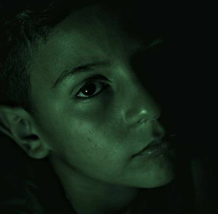 Primer plano de un niño en sombra, transmitiendo la experiencia de crecer con un psicópata en un ambiente oscuro y tenso.