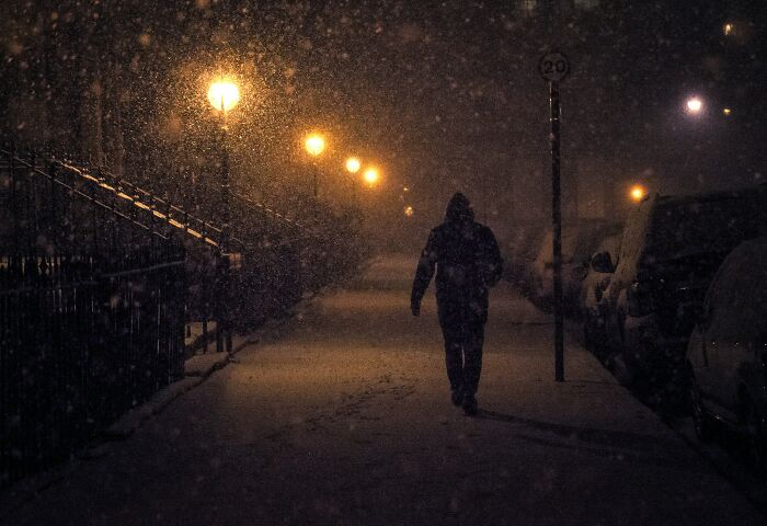 Persona caminando sola de noche bajo la nieve en calle oscura, ilustrando experiencias intensas en Reddit sin miedo.