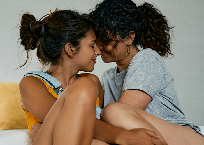 Mujer joven y suegra con expresión cercana y afectuosa compartiendo momento íntimo en casa, mostrando relación familiar.