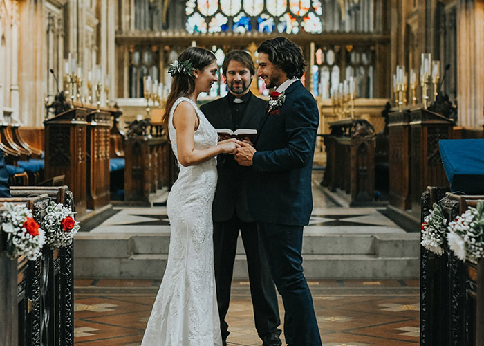 Pareja de novios en ceremonia de boda en iglesia, simbolizando las relaciones familiares y suegras en eventos importantes.