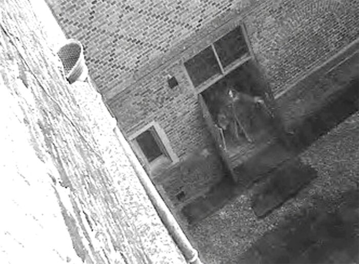 Foto real sin explicación clara muestra figura oscura en la entrada de un edificio de ladrillo antigua.