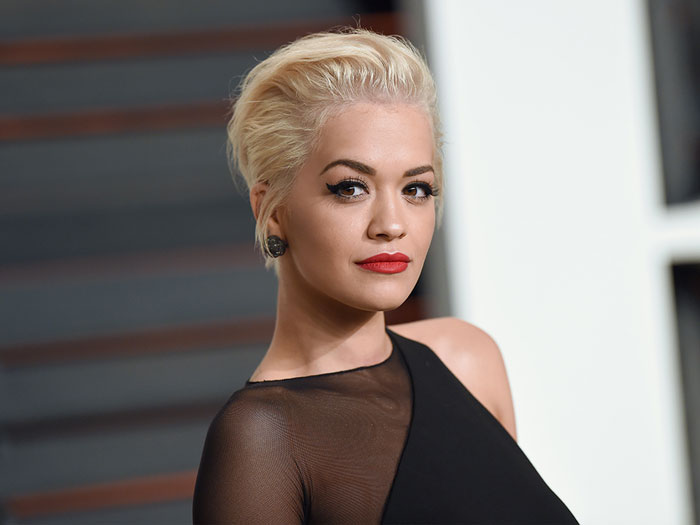 Mujer con cabello rubio corto y vestido negro elegante, representando momentos divertidos y oopsies memorables para SEO.