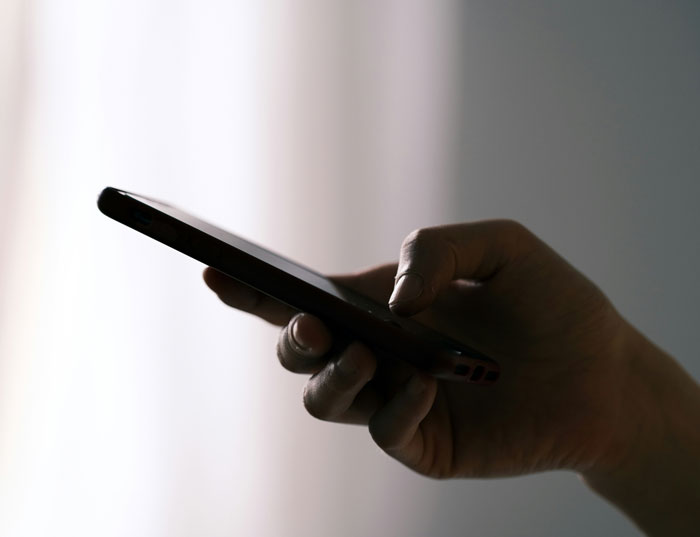 Mano sosteniendo un teléfono móvil en primer plano, destacando el uso de teléfonos para revelar verdades ocultas. Mano sosteniendo un teléfono móvil en primer plano, destacando el uso de teléfonos para revelar verdades ocultas.