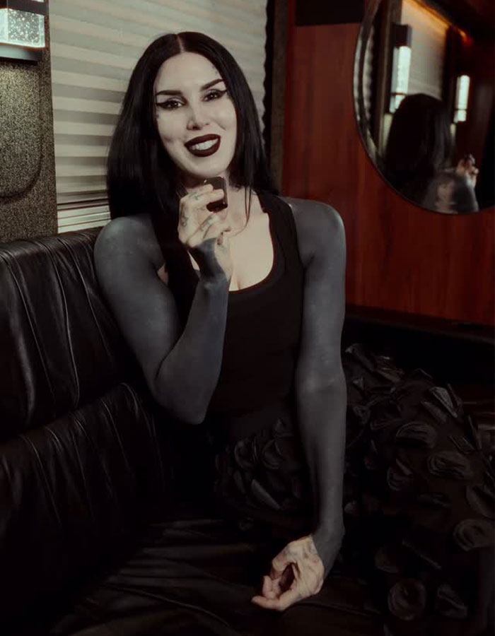 Kat Von D mostrando su transformación con tatuajes negros que cubren el 80% de su cuerpo, en un ambiente interior.
