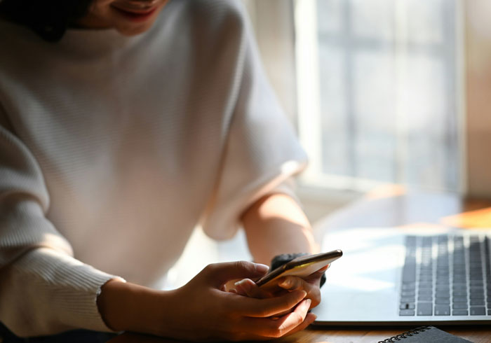 Persona con camiseta blanca usando teléfono móvil junto a laptop, ilustrando cómo los teléfonos ayudan a descubrir verdades ocultas. Persona con camiseta blanca usando teléfono móvil junto a laptop, ilustrando cómo los teléfonos ayudan a descubrir verdades ocultas.