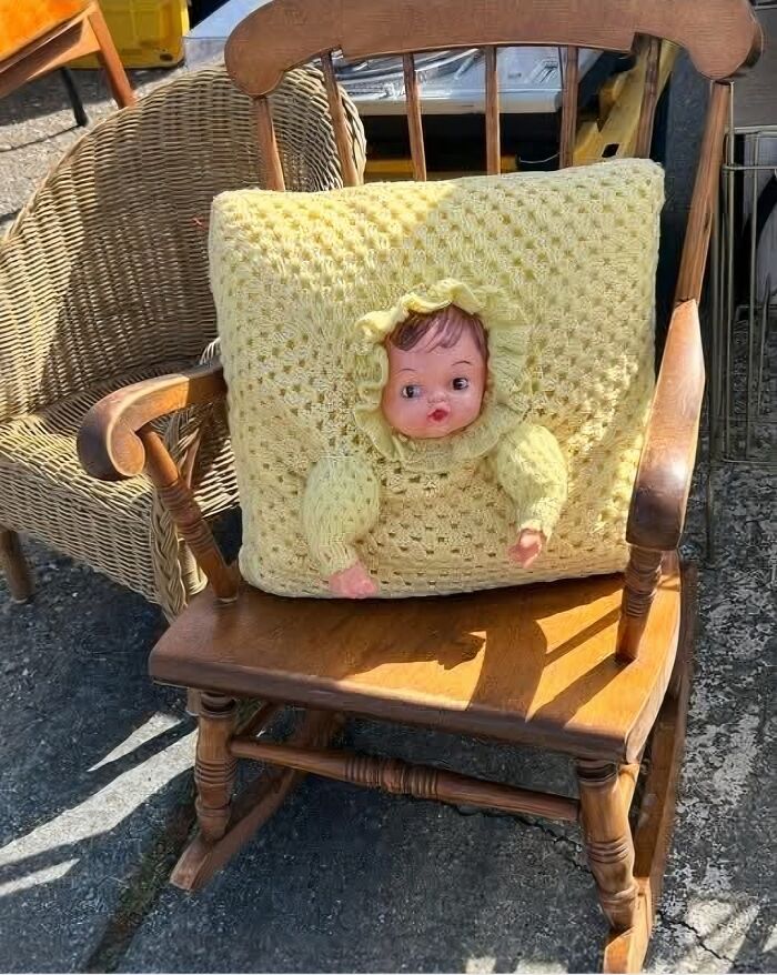 Cojín tejido a mano con muñeca incorporada en silla mecedora de madera, ejemplo de fallos DIY divertidos.