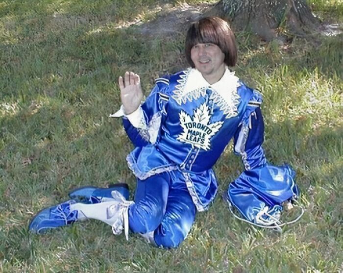 Hombre con uniforme azul brillante y diseño de hoja de arce, sentado en césped, ejemplo de uniformes hilarantes y extraños.