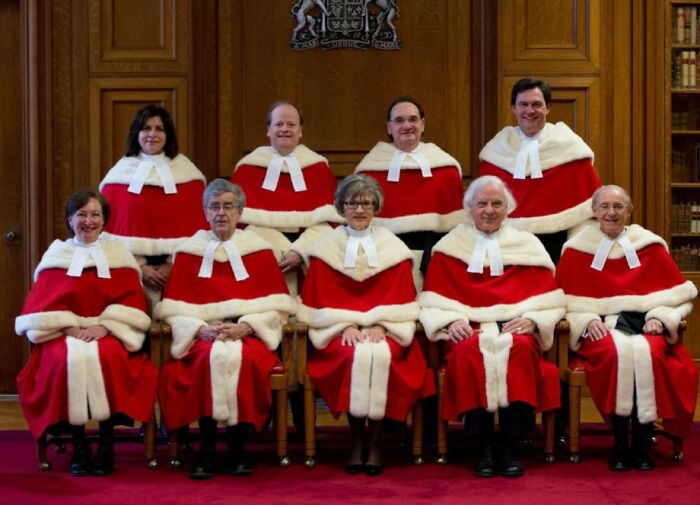 Grupo de personas en uniformes rojos y blancos llamativos que cuestionan el diseño de uniformes hilarantes.