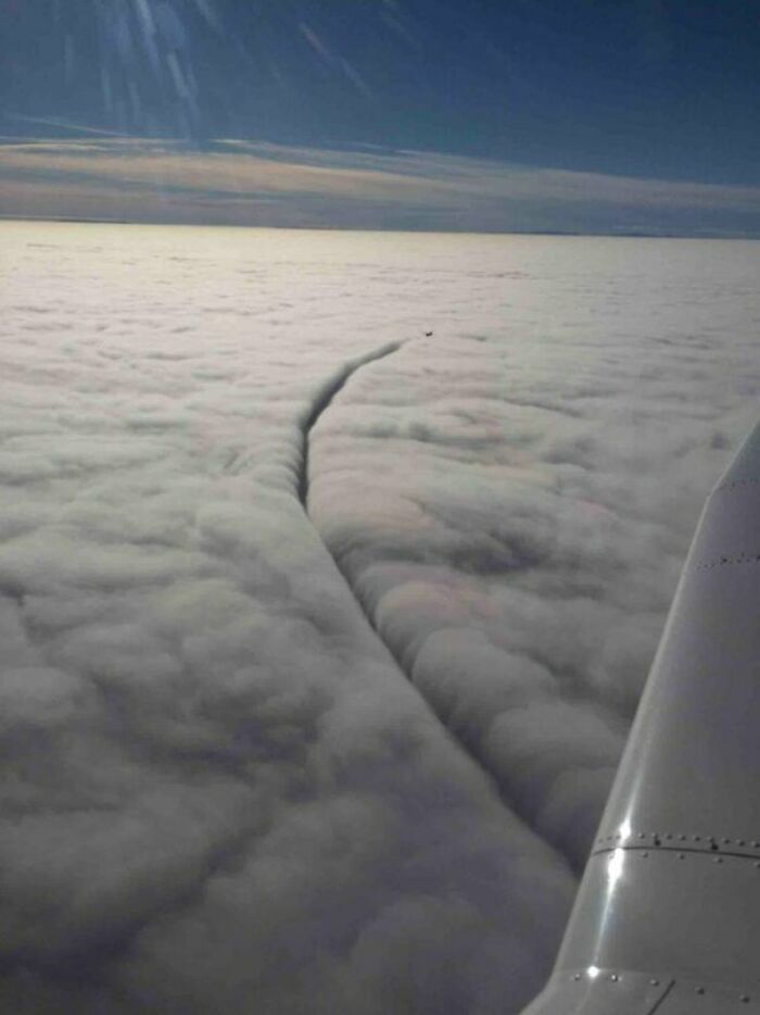 Vista aérea desde avión mostrando nubes con estela de avión abriendo un camino inesperado mejor que lo planeado en foto.