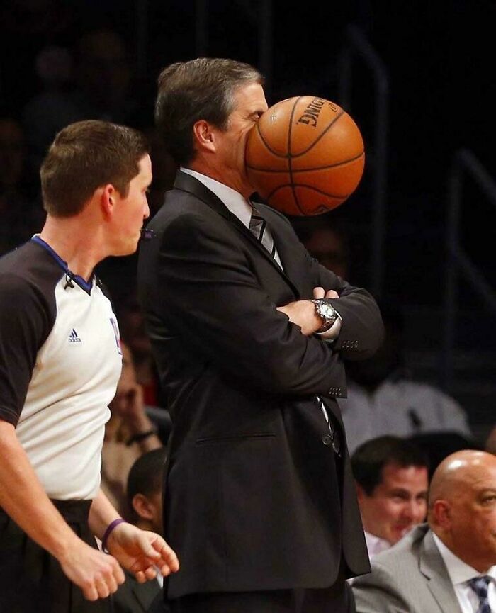 Hombre en traje recibiendo inesperadamente un balón de baloncesto en la cara, captura perfecta de foto mejor de lo esperado.