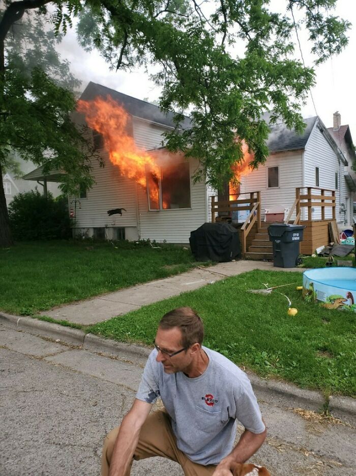 Hombre parado frente a una casa en llamas capturando un momento inesperado para una foto mejor de lo esperado.