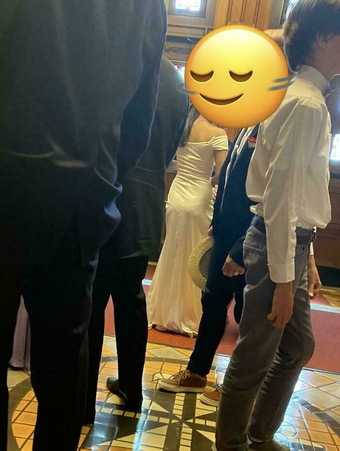Novios y invitados en boda, vestidos formales con énfasis en la novia con vestido blanco ajustado, momento capturado en interior.