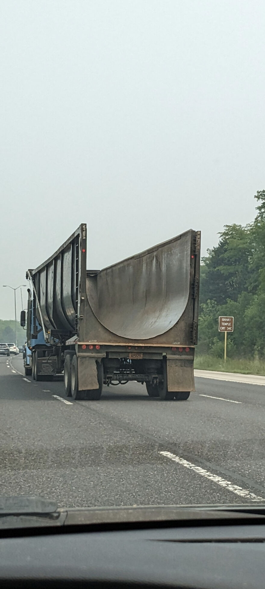 Camión especializado con remolque curvado usado para transportar cargas pesadas y voluminosas en carretera.