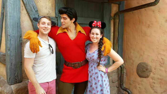 Personas con gran sentido del humor posando felices junto a personaje disfrazado en parque de diversiones divertido.