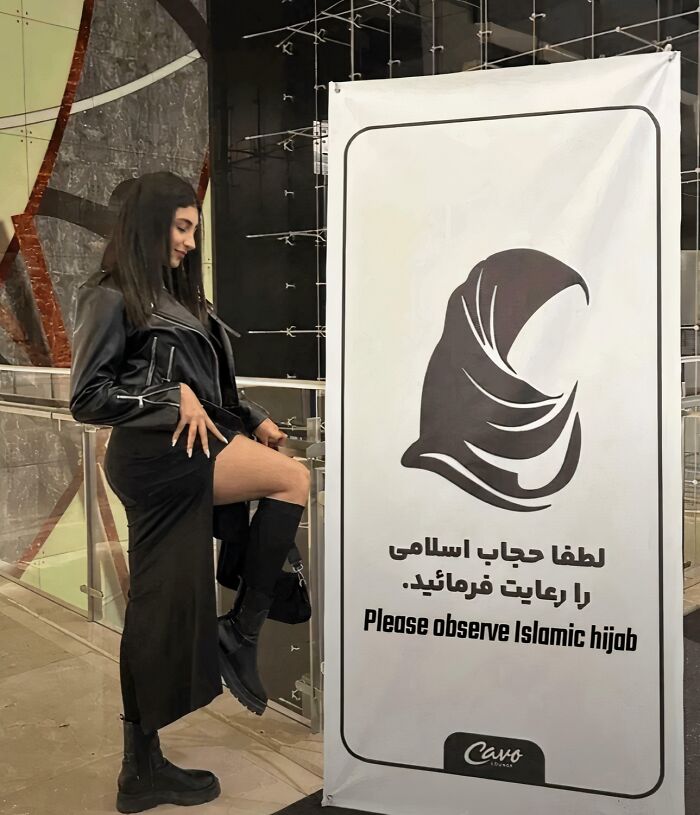 Mujer posando junto a cartel que pide observar el hijab islámico, ejemplo de Chaotic Good haciendo lo correcto a su manera.