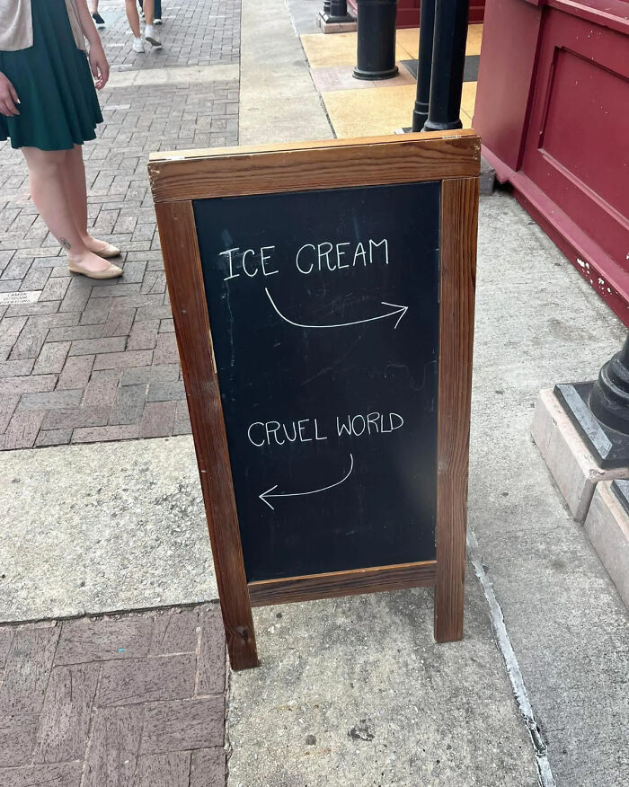 Cartel de pizarra con direcciones para helado y "mundo cruel", imagen extraña que se vuelve sagrada y maldita a la vez.