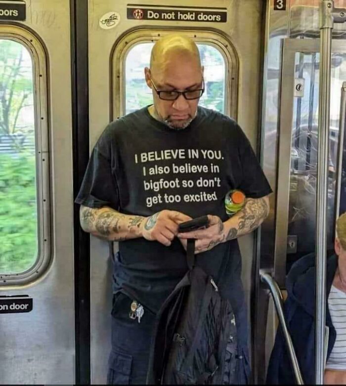 Hombre con camiseta divertida en el metro, imagen extraña que combina lo santo y maldito en fotos únicas y curiosas.