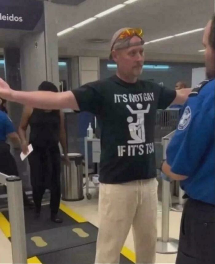 Hombre en control de seguridad con camiseta negra y gesto extraño en una foto extraña que se volvió sagrada y maldita.