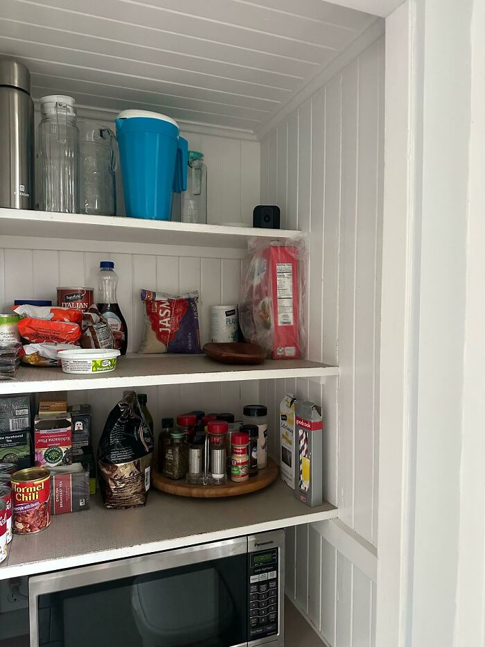 Estantes de despensa con alimentos variados y microondas, ejemplo de fotos de vacaciones que no salieron como se esperaba.